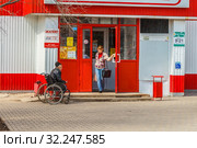 Russia, Samara, April 22, 2016: a sick man in a wheelchair asks for alms near the store, the text in Russian: a pharmacy. Редакционное фото, фотограф Акиньшин Владимир / Фотобанк Лори