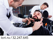 Male hairdresser accurately cutting beard of client. Стоковое фото, фотограф Яков Филимонов / Фотобанк Лори