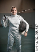 A young woman fencer standing in the school gym with a sword behind her back. Стоковое фото, фотограф Константин Шишкин / Фотобанк Лори