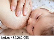 Infant feeding with female breast, close-up view at baby face and her mother breast. Стоковое фото, фотограф Кекяляйнен Андрей / Фотобанк Лори