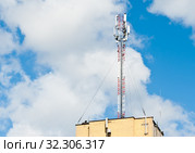 Антенна базовой станции мобильной связи на крыше здания на фоне голубого неба с белыми облаками (2019 год). Редакционное фото, фотограф E. O. / Фотобанк Лори