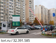 Белый легковой автомобиль въезжает в микрорайон "Новое Марфино" в Москве. Шлагбаум поднят (2019 год). Редакционное фото, фотограф Наталья Николаева / Фотобанк Лори
