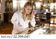 Woman visitor looking to art objects under glass with guide book in museum. Стоковое фото, фотограф Яков Филимонов / Фотобанк Лори