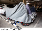 Motorcycles covered with safekeeping canvases standing in underground parking lot for winter keeping. Стоковое фото, фотограф Кекяляйнен Андрей / Фотобанк Лори