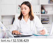 Practicioner girl in medical uniform is working with documents and laptop. Стоковое фото, фотограф Яков Филимонов / Фотобанк Лори