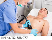 Woman doctor is doing vacuum massage procedure on belly of adult client. Стоковое фото, фотограф Яков Филимонов / Фотобанк Лори