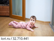 Six month baby trying to creep on laminate floor in domestic room. Стоковое фото, фотограф Кекяляйнен Андрей / Фотобанк Лори