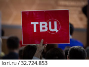 Корреспондент телеканала ТВЦ держит табличку с названием канала во время большой ежегодной пресс-конференции Владимира Путина, Россия (2019 год). Редакционное фото, фотограф Николай Винокуров / Фотобанк Лори