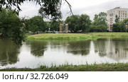 The Vorontsov Park at rainy cloudy day. Rain drops fall on water surface. Dormitory district with dwelling houses is in Kirovsky district, St. Petersburg city, Russia (2019 год). Стоковое видео, видеограф Кекяляйнен Андрей / Фотобанк Лори
