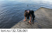Tired young girl dressed wetsuit gets out from water on wooden pier, diving in lake. Стоковое видео, видеограф Кекяляйнен Андрей / Фотобанк Лори