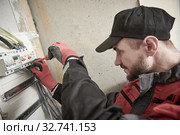 Electrician works with switchbox. installing circuit breaker. Стоковое фото, фотограф Дмитрий Калиновский / Фотобанк Лори