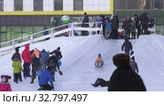 Дети катаются с ледяной горки на городской площади. Children ride on an ice slide in the town square. (2019 год). Редакционное видео, видеограф Евгений Романов / Фотобанк Лори