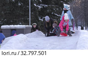 Дети катаются с ледяной горки на городской площади. Children ride on an ice slide in the town square. (2019 год). Редакционное видео, видеограф Евгений Романов / Фотобанк Лори