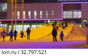 Дети катаются с ледяной горки на городской площади. Children ride on an ice slide in the town square. (2019 год). Редакционное видео, видеограф Евгений Романов / Фотобанк Лори
