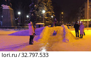 Дети катаются с ледяной горки на городской площади. Children ride on an ice slide in the town square. (2019 год). Редакционное видео, видеограф Евгений Романов / Фотобанк Лори