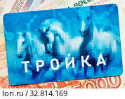 Транспортная карта «Тройка» на фоне денежных купюр (2020 год). Редакционное фото, фотограф E. O. / Фотобанк Лори