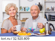 Smiling elderly spouses enjoying tea with sweets. Стоковое фото, фотограф Яков Филимонов / Фотобанк Лори