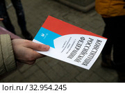 Женщина держит в реку брошюру с Конституцией Российской Федерации на центральной улице в городе Москве, Россия (2020 год). Редакционное фото, фотограф Николай Винокуров / Фотобанк Лори