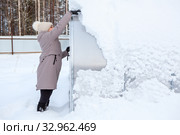 Mature woman clears the snow away from greenhouse at winter season. Стоковое фото, фотограф Кекяляйнен Андрей / Фотобанк Лори