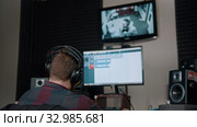 A man sound engineer watching the rapper whlie recording his track. Стоковое видео, видеограф Константин Шишкин / Фотобанк Лори