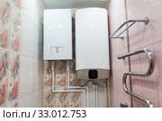 Heat and hot water supply systems are on wall of bathroom. Electric boiler for central heating and tank for warming water. Стоковое фото, фотограф Кекяляйнен Андрей / Фотобанк Лори