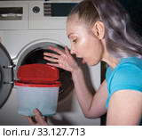 Woman in the background of a washing machine peeps in surprise in box with washing gel in her hands, photo from the series. Стоковое фото, фотограф Куликов Константин / Фотобанк Лори