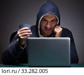 Young man wearing a hoodie sitting in front of a laptop computer. Стоковое фото, фотограф Elnur / Фотобанк Лори