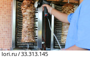 Cooking traditional fast food doner kebab meat on a rotary grill. Стоковое видео, видеограф FotograFF / Фотобанк Лори