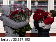 Мужчины несут купленные на Рижском цветочном рынке букеты роз в канун Международного женского дня - 8 марта в городе Москве, Россия (2020 год). Редакционное фото, фотограф Николай Винокуров / Фотобанк Лори