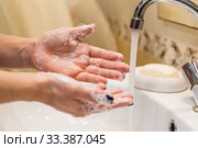 Person holding his hands with soap foam under water stream, close up view. Стоковое фото, фотограф Кекяляйнен Андрей / Фотобанк Лори