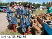 Три женщины в красивых костюмах подходят к прилавку с берестяными изделиями на фестивале музыки и ремёсел Каратаг. Красноярский край. (2019 год). Редакционное фото, фотограф Светлана Попова / Фотобанк Лори