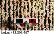 Defocused dynamic background of garlands from popcorn and golden sparkling tinsel. Garlands of popcorn for sports and movie news. In foreground 3D glasses, anaglyph. 4K video. Стоковое видео, видеограф Dmitry Domashenko / Фотобанк Лори