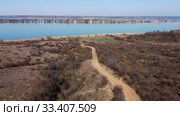Aerial view, flying over a dirt road in steppe, in the background the pond and village. Camera moving forwards above steppe to the pond side. Khadzhibey Estuary, Odessa region, Ukraine. Стоковое видео, видеограф Некрасов Андрей / Фотобанк Лори