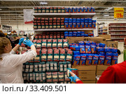 Сотрудник магазина выкладывает упаковки гречки и риса в магазине торговой сети АШАН в торговом центре МЕГА в Химках, Россия (2020 год). Редакционное фото, фотограф Николай Винокуров / Фотобанк Лори