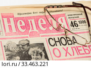 Старая газета и очки на белом фоне (2019 год). Редакционное фото, фотограф Игорь Низов / Фотобанк Лори