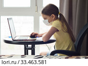 Девочка в медицинской маске смотрит онлайн урок в ноутбуке. Стоковое фото, фотограф Иванов Алексей / Фотобанк Лори