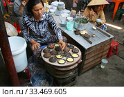 Женщина готовит традиционный вьетнамский омлет (Banh can). Рынок Чо Дам (Cho Dam). Вьетнам, город Нячанг (2015 год). Редакционное фото, фотограф Щеголева Ольга / Фотобанк Лори