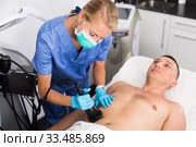 Woman doctor is doing vacuum massage procedure on belly of adult client. Стоковое фото, фотограф Яков Филимонов / Фотобанк Лори