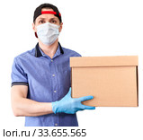 Courier with cardboard box from delivery service, man with medical mask and blue neoprene gloves, isolated on white background. Стоковое фото, фотограф Кекяляйнен Андрей / Фотобанк Лори
