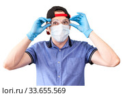 Deliveryman put on plastic glasses, medical mask with hands with blue neoprene gloves, isolated on white background. Стоковое фото, фотограф Кекяляйнен Андрей / Фотобанк Лори