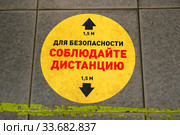 "Для безопасности соблюдайте дистанцию 1,5 метра". Яркая желтая предупреждающая наклейка на полу в торговом зале в продуктовом магазине. Пандемия коронавируса COVID-19 в Москве (2020 год). Стоковое фото, фотограф Щеголева Ольга / Фотобанк Лори
