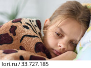 Девочка неспешно просыпается, лежа в кровати и накрывшись старым одеялом. Стоковое фото, фотограф Иванов Алексей / Фотобанк Лори