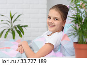 Счастливая десятилетняя девочка утром лежит в кровати и улыбаясь смотрит в кадр. Стоковое фото, фотограф Иванов Алексей / Фотобанк Лори