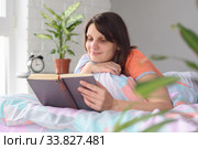 Девушка дома утром проснувшись принялась читать любимую книгу. Стоковое фото, фотограф Иванов Алексей / Фотобанк Лори
