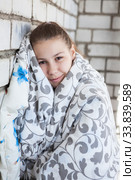 Preteen girl standing near brick wall wrapping with thick cozy blanket. Стоковое фото, фотограф Кекяляйнен Андрей / Фотобанк Лори