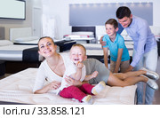 attractive young woman with husband and sons testing mattress in store. Стоковое фото, фотограф Яков Филимонов / Фотобанк Лори