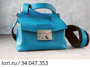 fashionable turquoise Crossbody bag on the gray concrete background. Blue crossbody bag made of sheepskin and cowhide leather, a metal clasp. Стоковое фото, фотограф Nataliia Zhekova / Фотобанк Лори