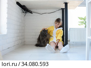 Наказанная девочка сидит под столом и гладит домашнего кота. Стоковое фото, фотограф Иванов Алексей / Фотобанк Лори