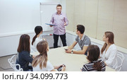 Friendly lawyer sitting with laptop in informal office meeting space, consulting his young female clients. Стоковое видео, видеограф Яков Филимонов / Фотобанк Лори