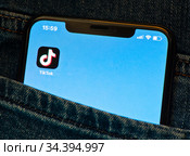 Приложение TikTok ("ТикТок") на экране мобильного телефона, лежащего в кармане джинсов (крупным планом) (2020 год). Редакционное фото, фотограф E. O. / Фотобанк Лори